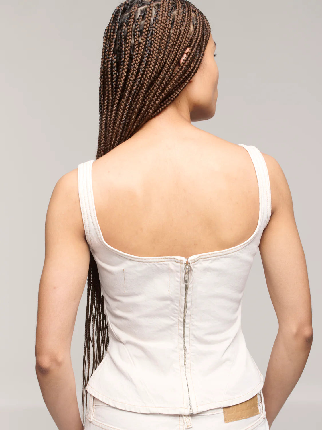 Person wearing a white sleeveless top with a gray background