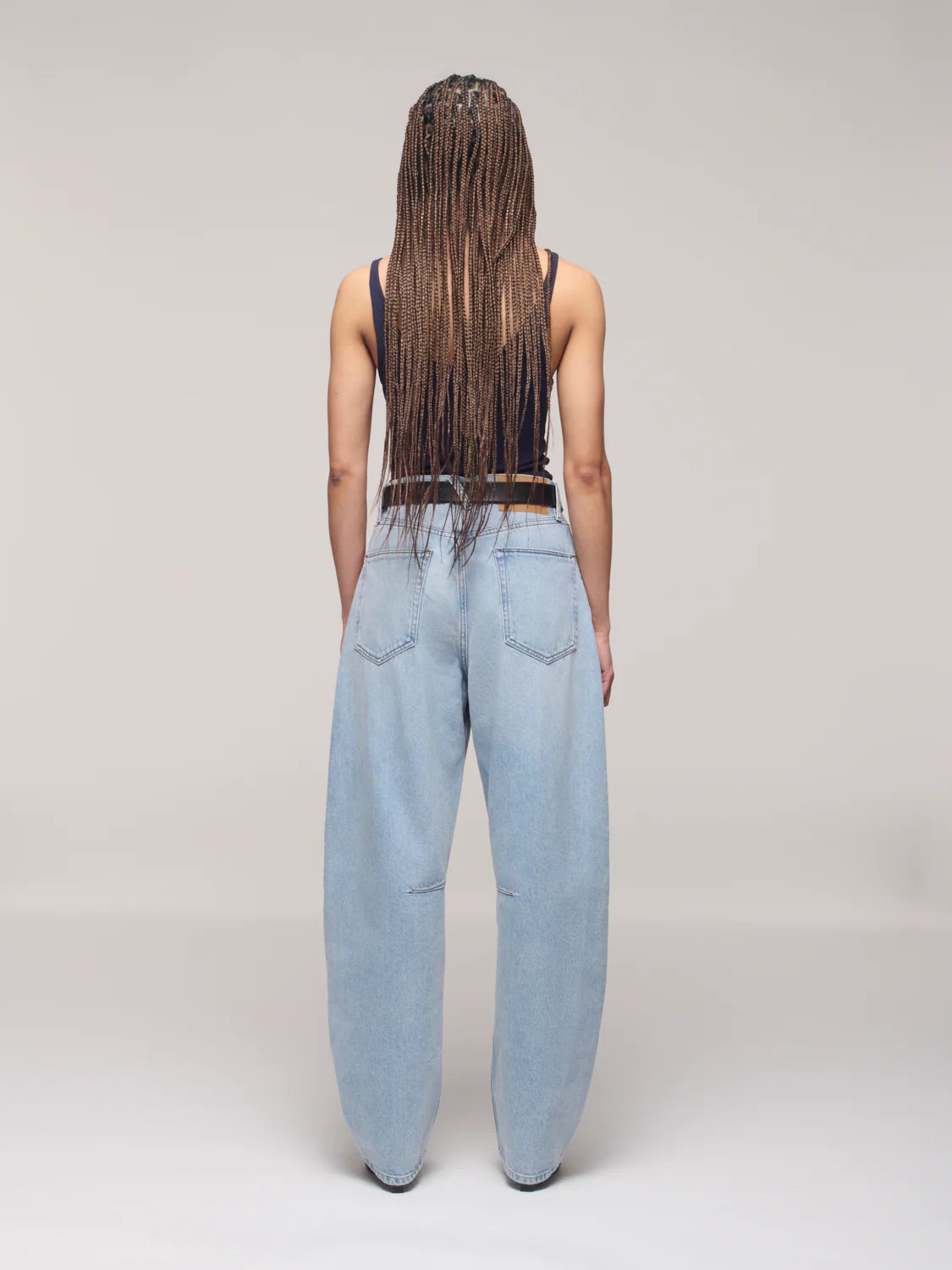 Person wearing light blue jeans and a black top on a plain background