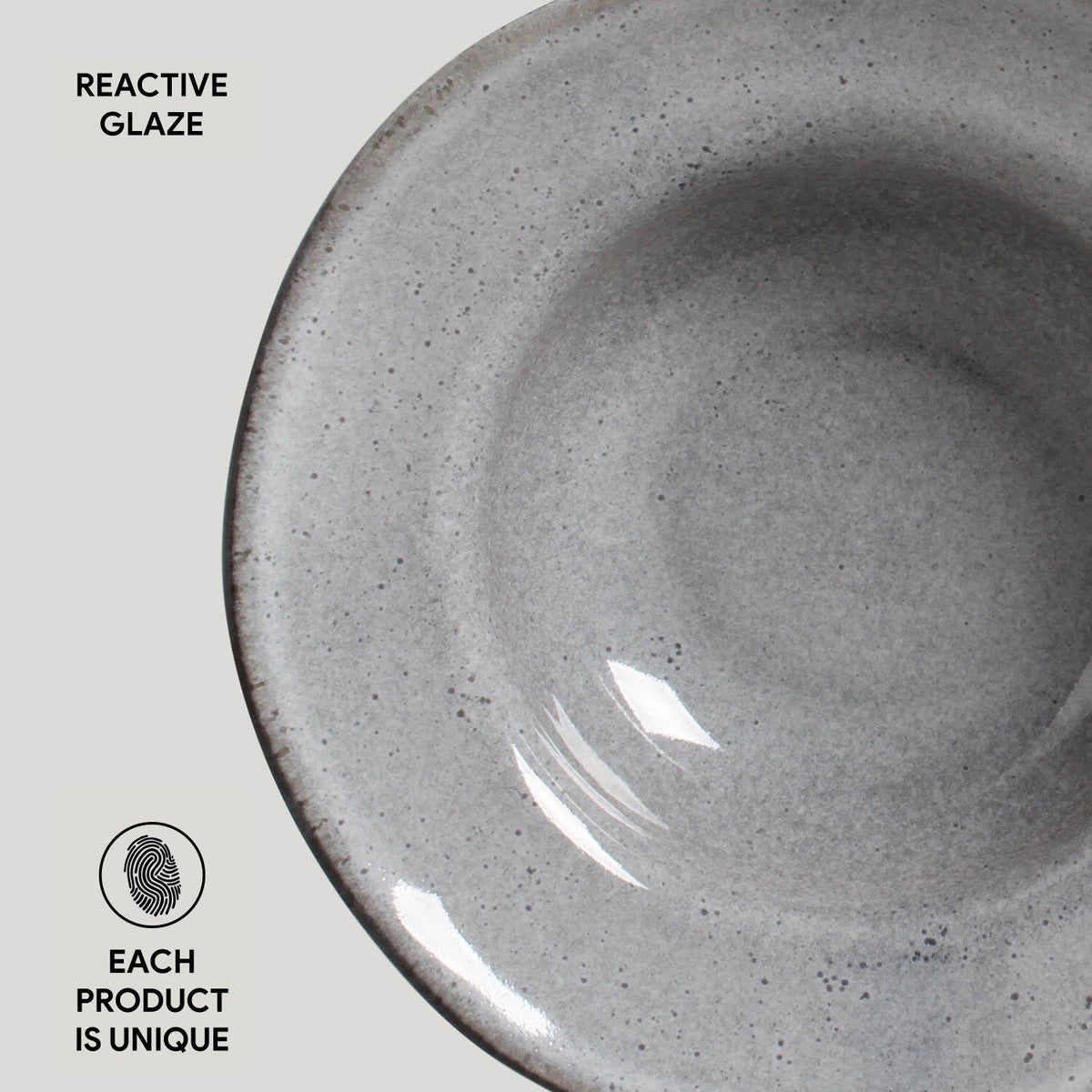 Close-up of a gray ceramic bowl with reactive glaze on a light gray background.