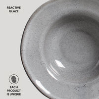Close-up of a gray ceramic bowl with reactive glaze on a light gray background.