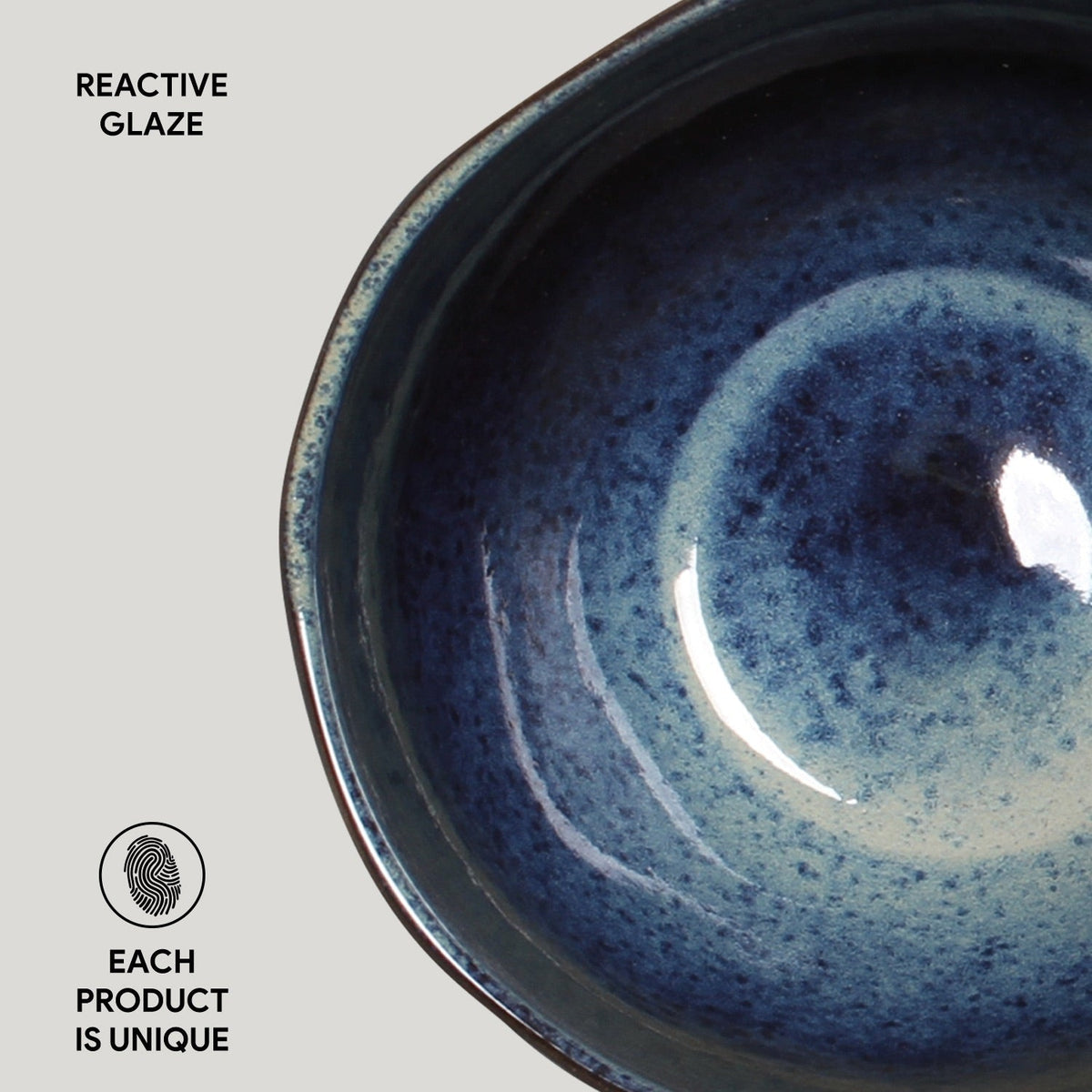 Close-up of a blue ceramic bowl with reactive glaze on a light gray background