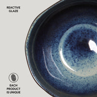 Close-up of a blue ceramic bowl with reactive glaze on a light gray background