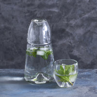 Pebbled Glass Bedside Carafe Set with mint water on a gray surface