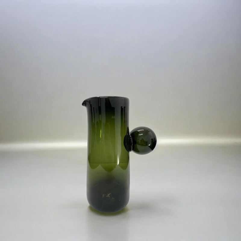 Green glass pitcher vase with a spherical accent handle on a white background