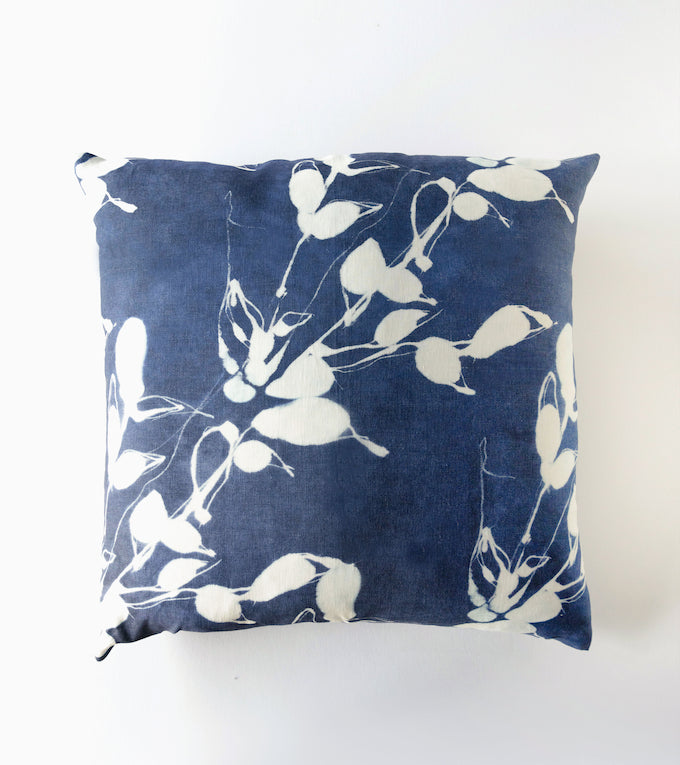 Blue pillow with white floral pattern on a white background