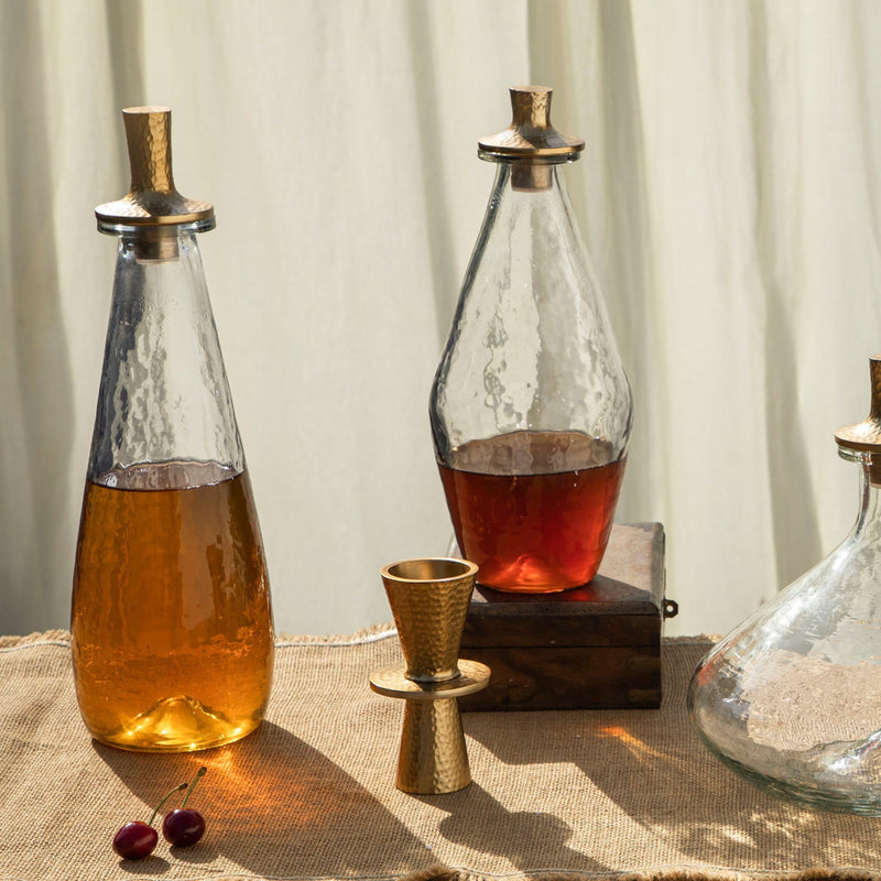 Pebbled glass decanters filled with liquids on a natural surface
