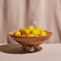 Wooden bowl filled with lemons on a beige background