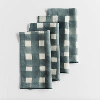 Set of four blue-grey and white checkered napkins on a light gray background