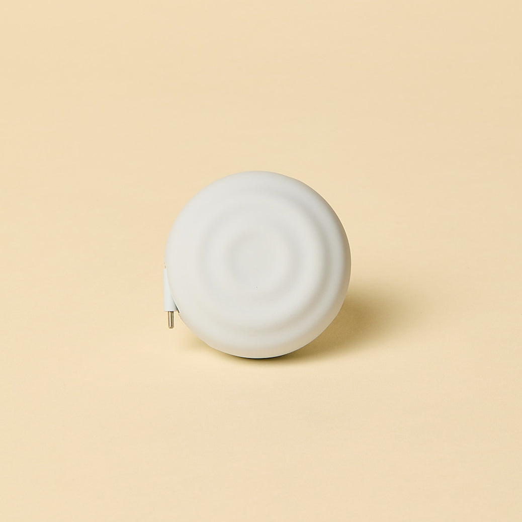White spherical object with a charging cord on a beige background