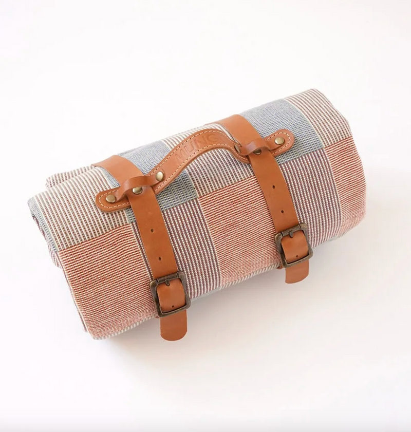Roll-up picnic blanket with brown straps on a white background