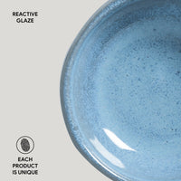 Close-up of a blue ceramic plate with reactive glaze on a light gray background.
