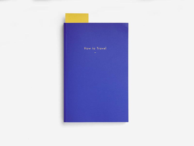 Blue book titled 'How to Travel' with a gold top on a white background