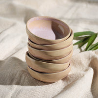 Stack of ceramic ramekins on a textured fabric surface with a plant leaf in the background