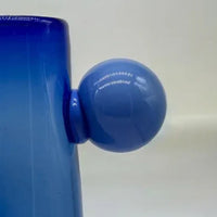 Close-up of a blue container with a round blue handle on a white background