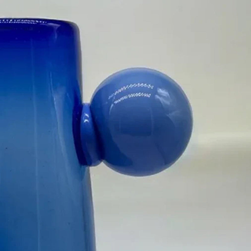 Close-up of a blue container with a round blue handle on a white background