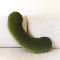 Green U-shaped pillow on a beige sofa