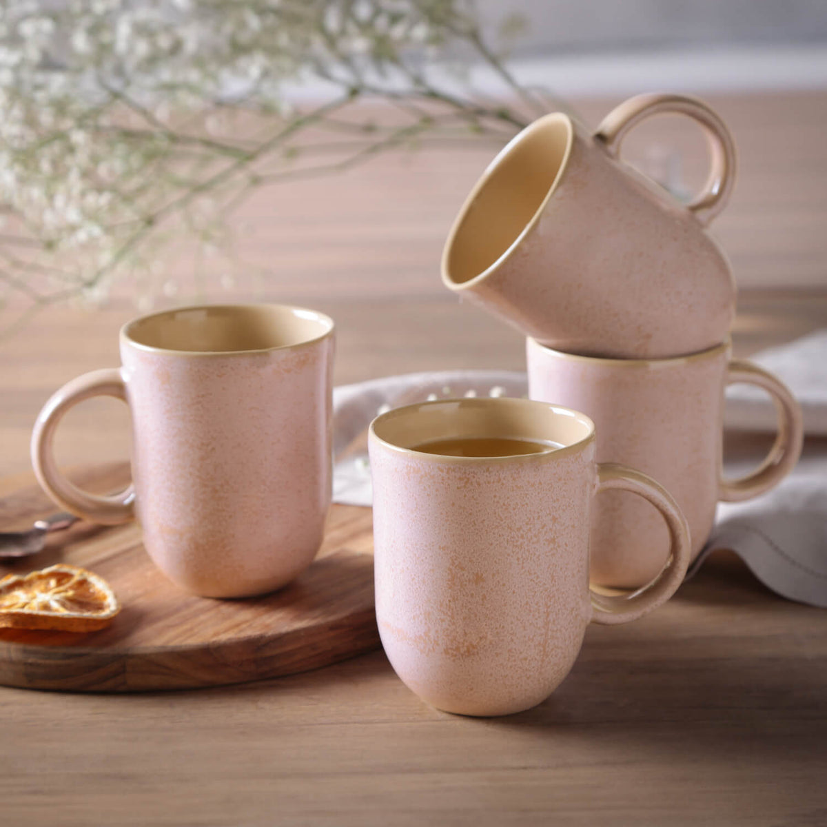 Set of 4 ceramic mugs on a wooden surface with a blurred background