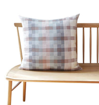 Plaid pillow on a wooden bench with a white background