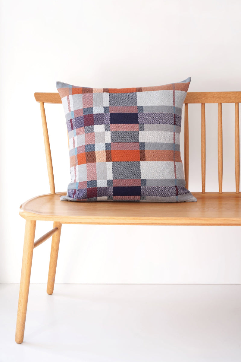 Plaid pillow on a wooden chair against a white background