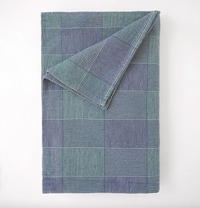 Folded blue and green checkered blanket on a white background