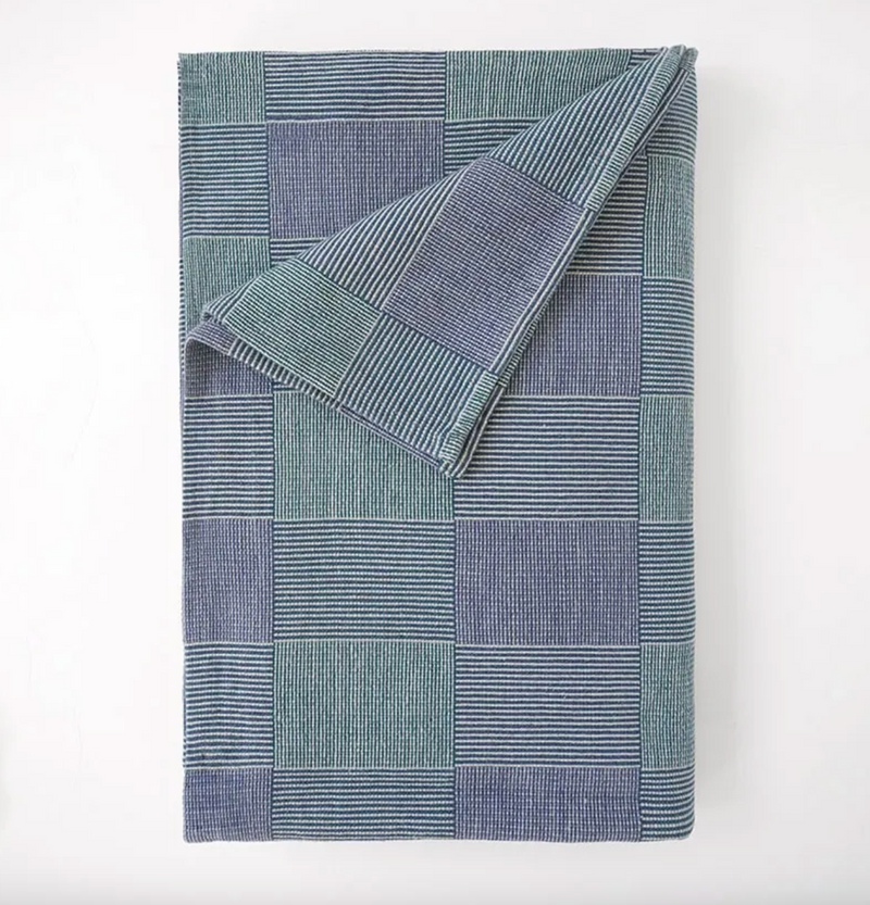 Folded blue and green checkered blanket on a white background