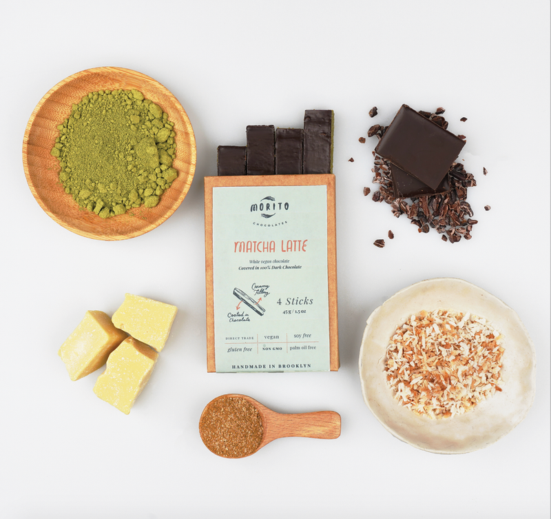Matcha latte chocolate ingredients including matcha powder, chocolate bars, and coconut flakes on a white background.