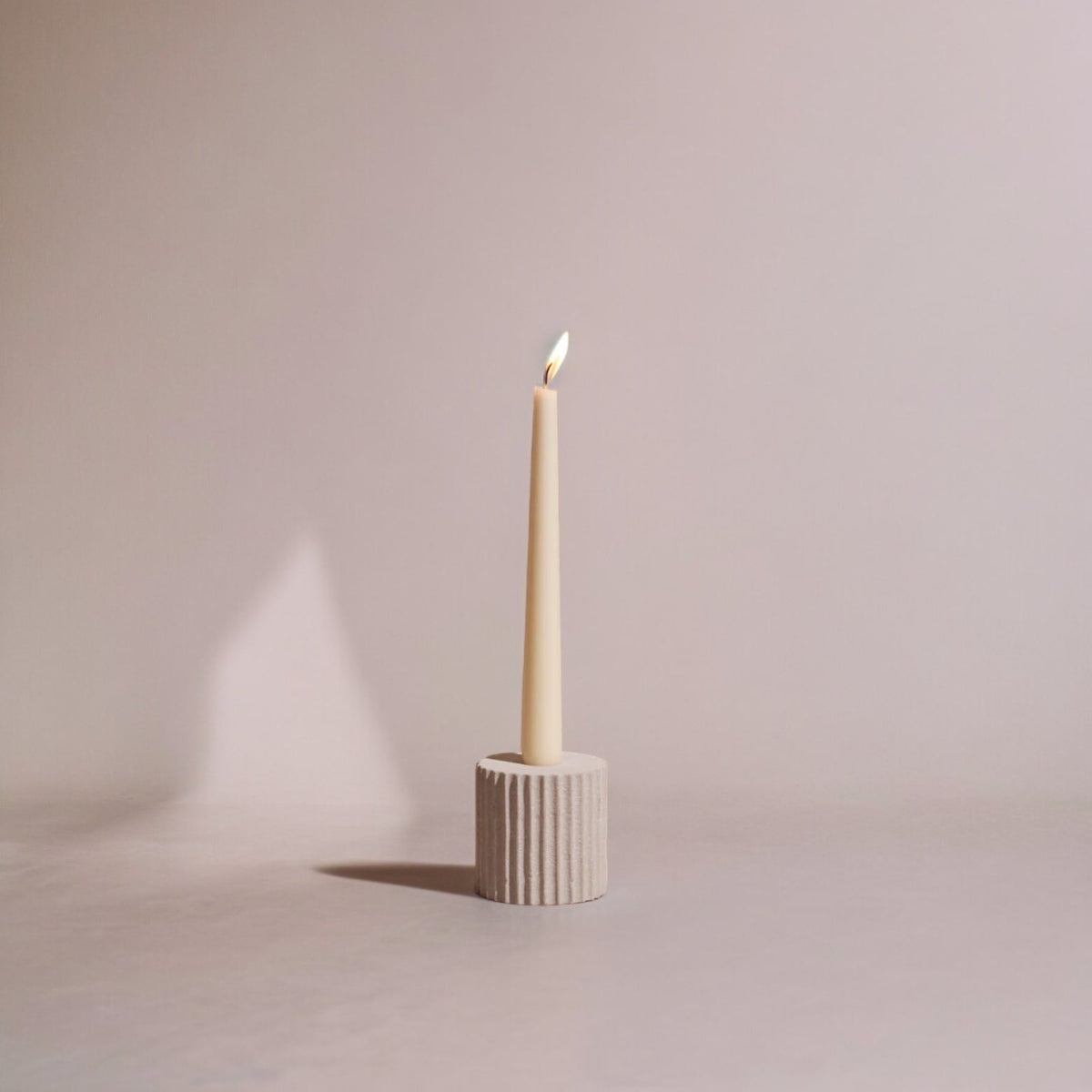 Candle in a textured soapstone holder on a plain background