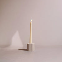 Candle in a textured soapstone holder on a plain background