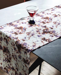 Marble patterned table runner on a table with a glass of red liquid.