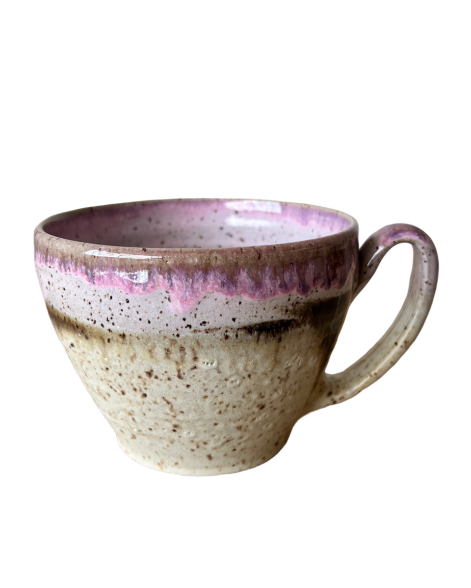 Ceramic mug with light and dark neutral and pink glaze details on a white background