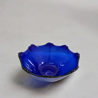 Blue glass bowl with wavy rim on a light gray background