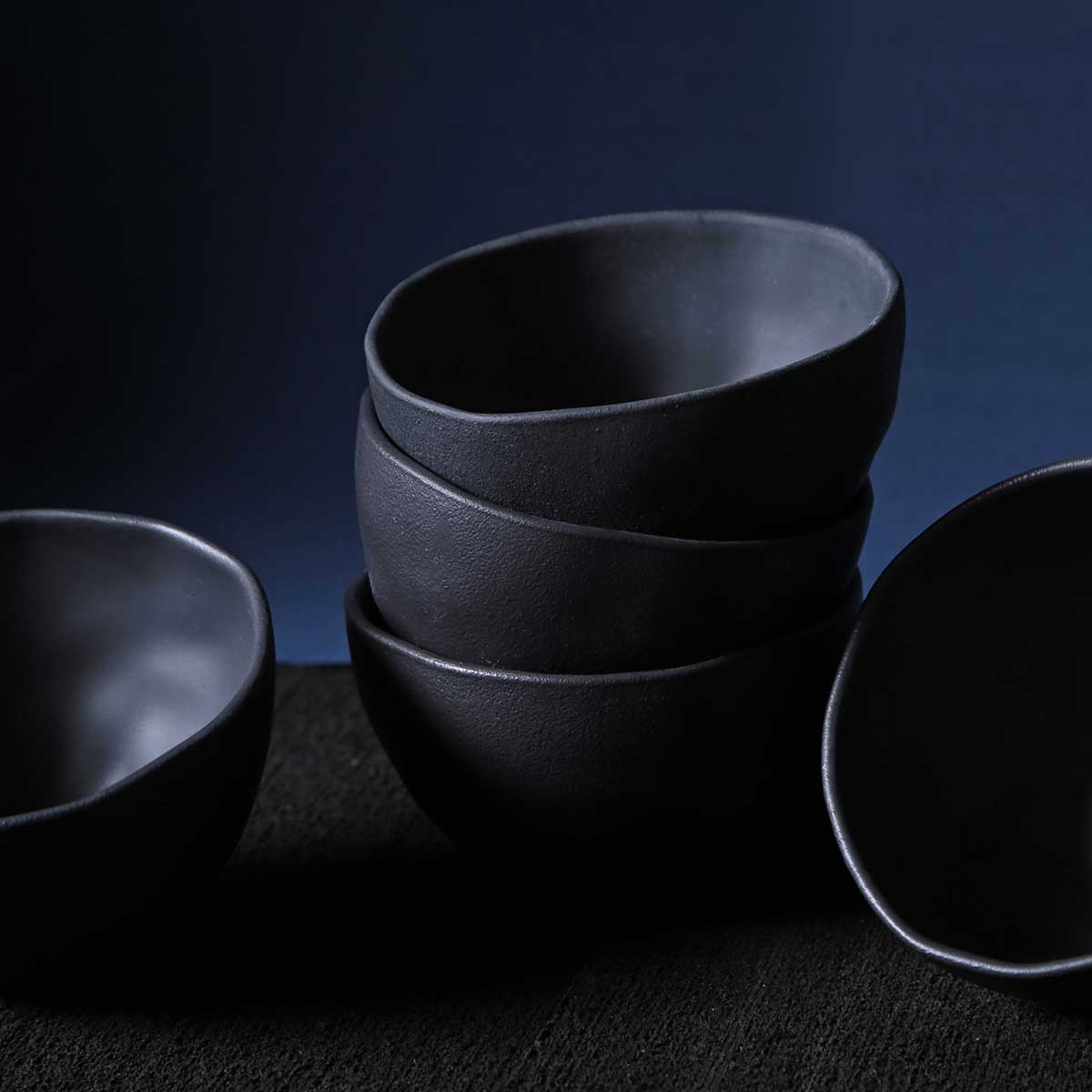 Stack of black ceramic bowls on a dark background