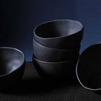 Stack of black ceramic bowls on a dark background