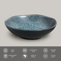 Speckled blue and black ceramic bowl on a light gray background