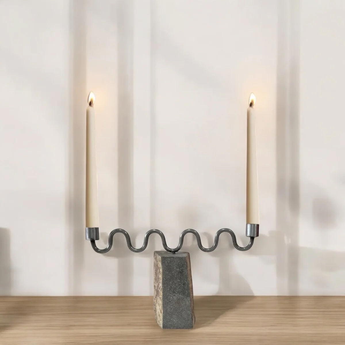 Candle holder with two lit candles on a wooden surface and light gray background