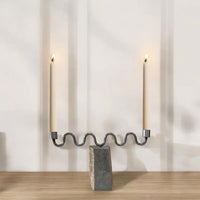 Candle holder with two lit candles on a wooden surface and light gray background