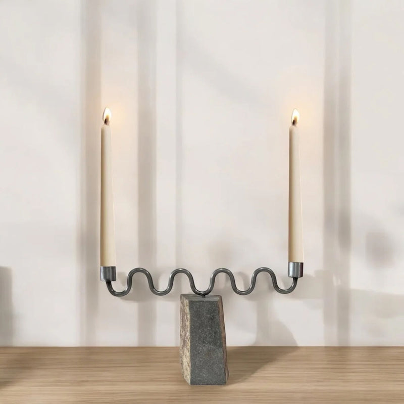 Candle holder with two lit candles on a wooden surface and light gray background
