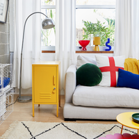 Living room with a yellow cabinet, gray sofa, and colorful pillows.