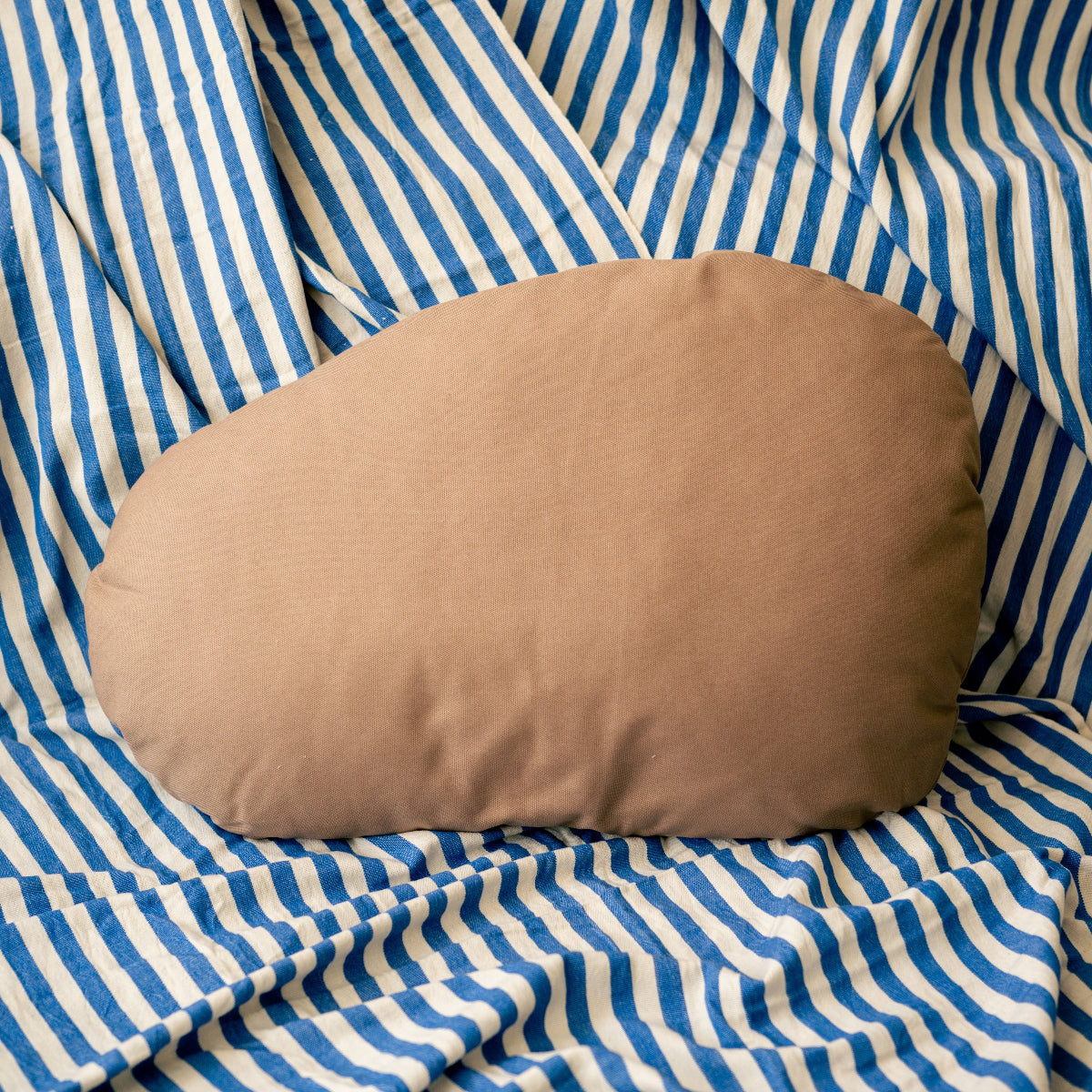 Brown pillow on a blue and white striped fabric background