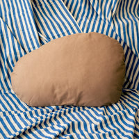 Brown pillow on a blue and white striped fabric background