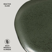 Green ceramic plate with reactive glaze on a light gray background
