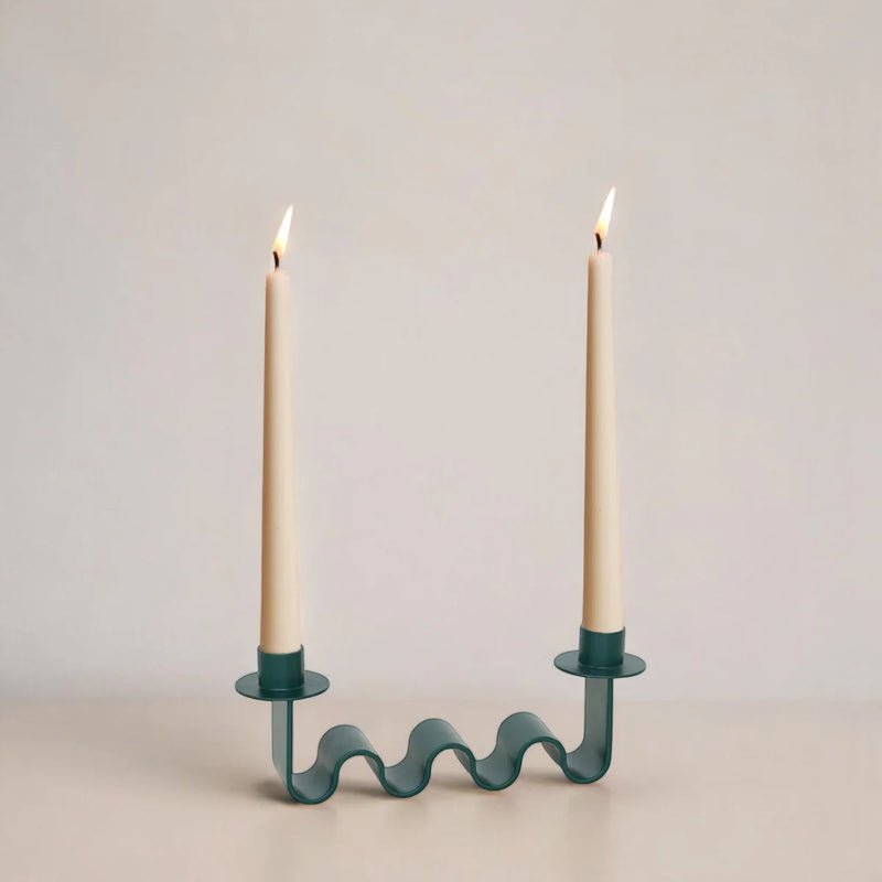 Wavy candle holder with two lit candles on a plain background