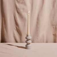 Candle in a decorative holder against a beige fabric background