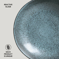 Close-up of a ceramic plate with reactive glaze texture on a light gray background.