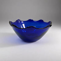 Blue glass bowl with wavy edge on a gray background