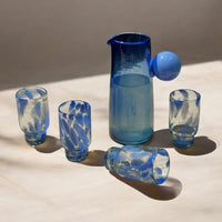 Set of blue glassware including a pitcher on a light surface.