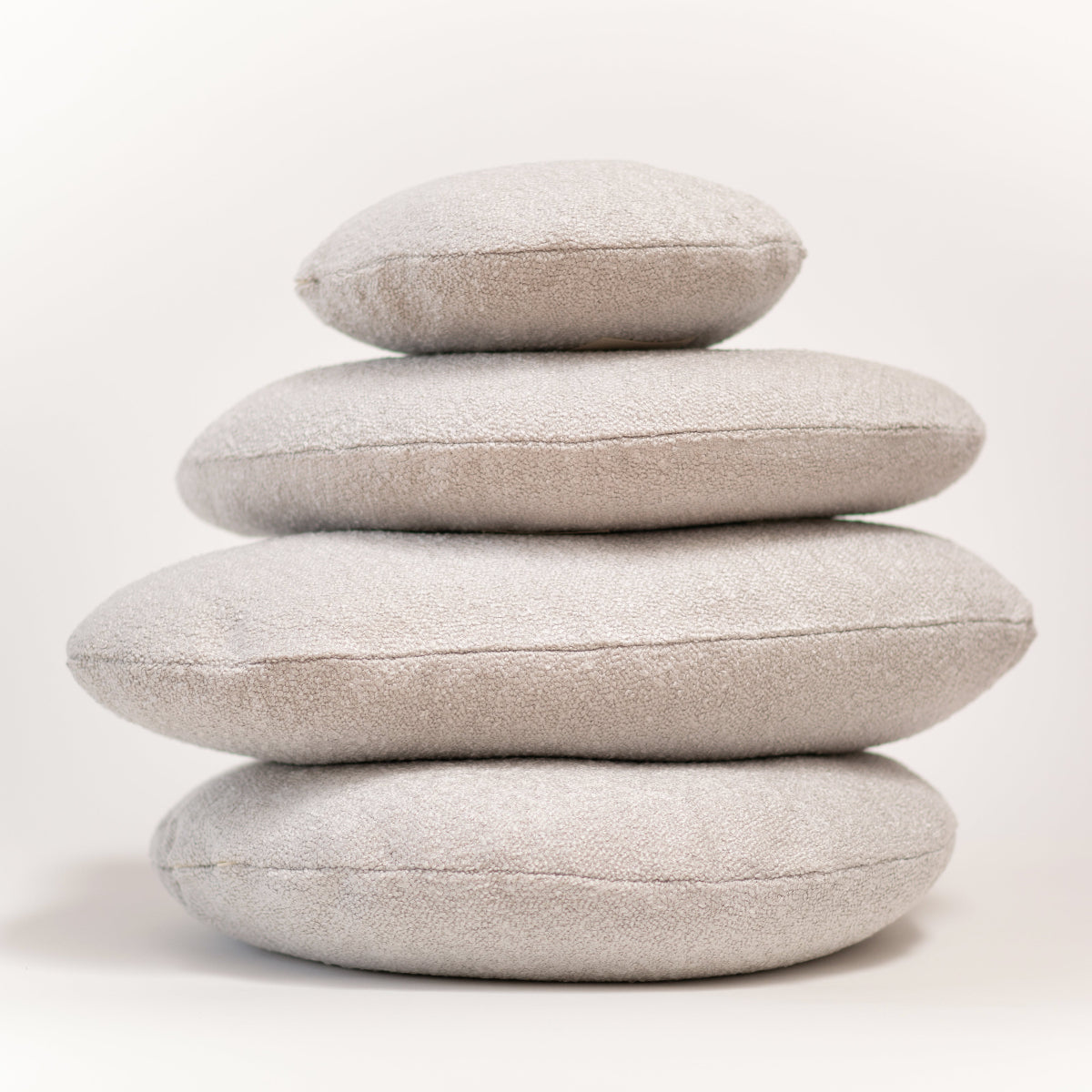 Stack of four light gray cushions on a white background