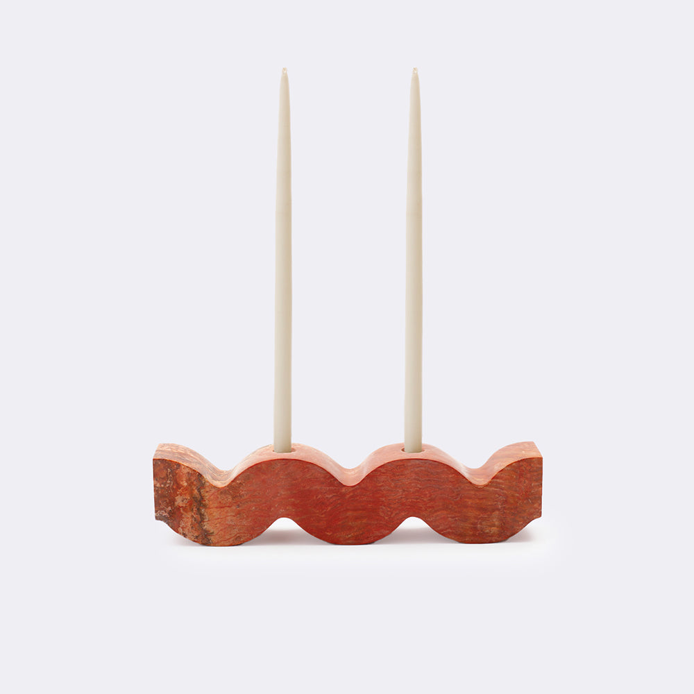 Orange stone wavy candle holder with two taper candles on a white background