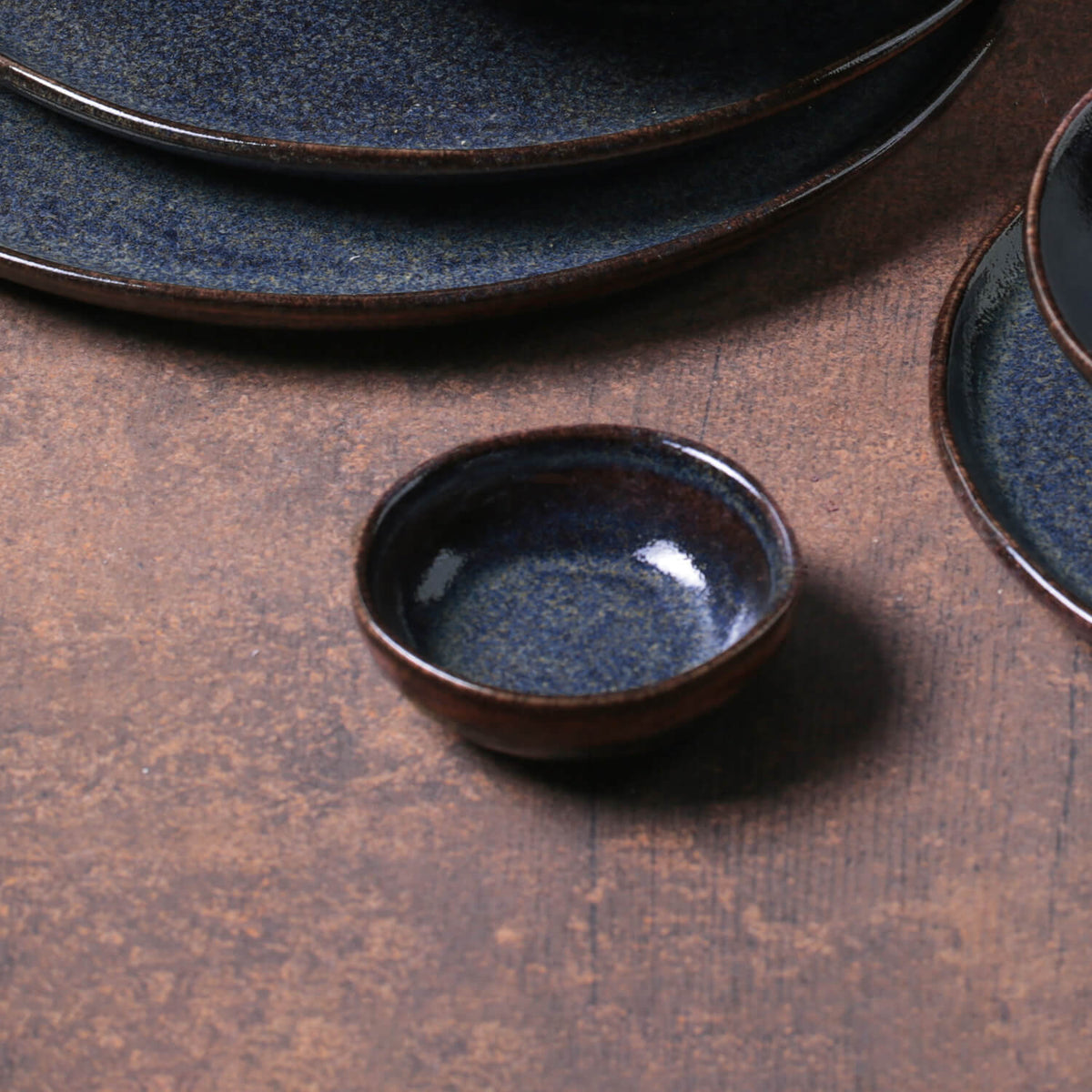Set of dark blue ceramic ramekins on a brown surface