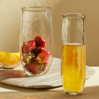Pebbled glasses filled with champagne and strawberries on a neutral surface